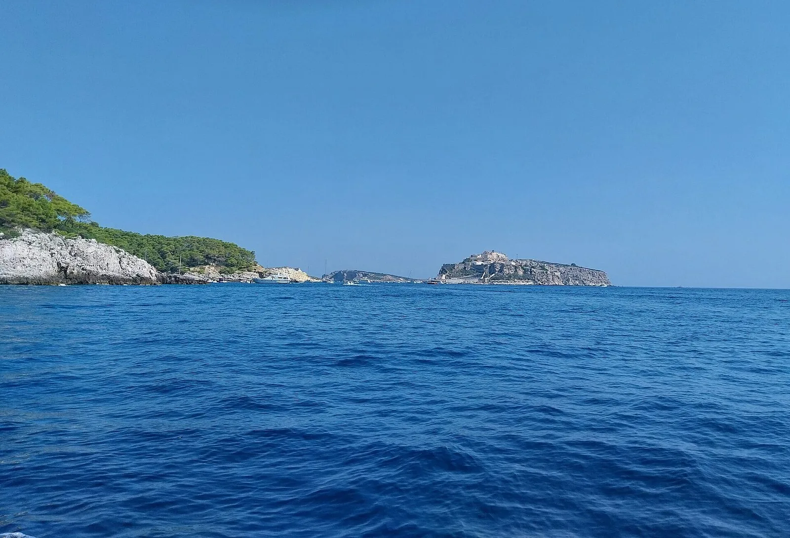 Il mare blu intenso con a sinistra la costa rocciosa e la pineta di San Domino e al centro l'isola di San Nicola con il complesso fortificato dell'abbazia