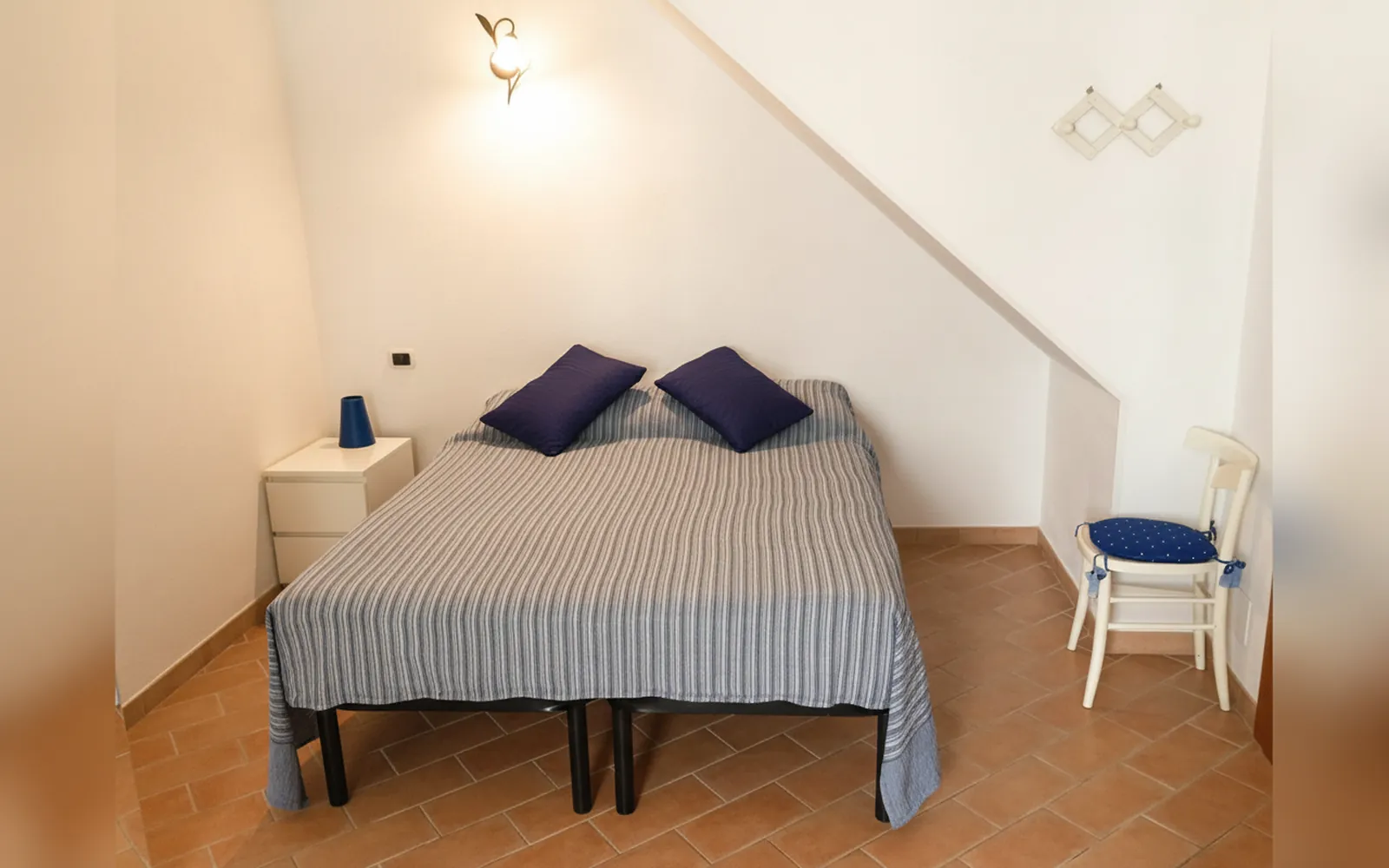 Il letto matrimoniale con i cuscini blu, sotto il soffitto in pendenza